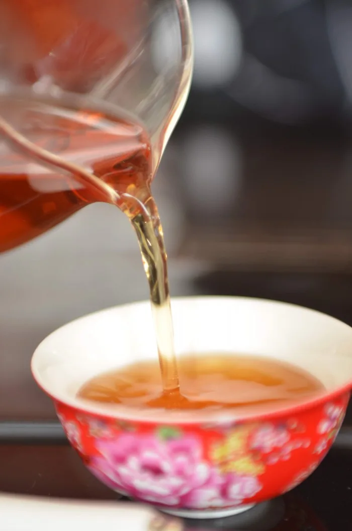 以公道杯將紅茶倒入花瓷茶杯